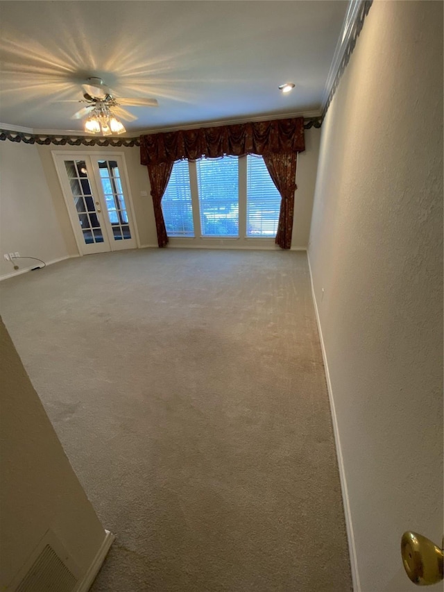 empty room featuring crown molding, french doors, a ceiling fan, baseboards, and light colored carpet
