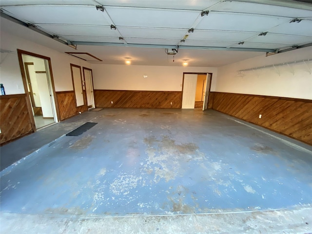 garage with a wainscoted wall, wood walls, and a garage door opener