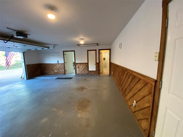garage with a wainscoted wall, a garage door opener, and wooden walls
