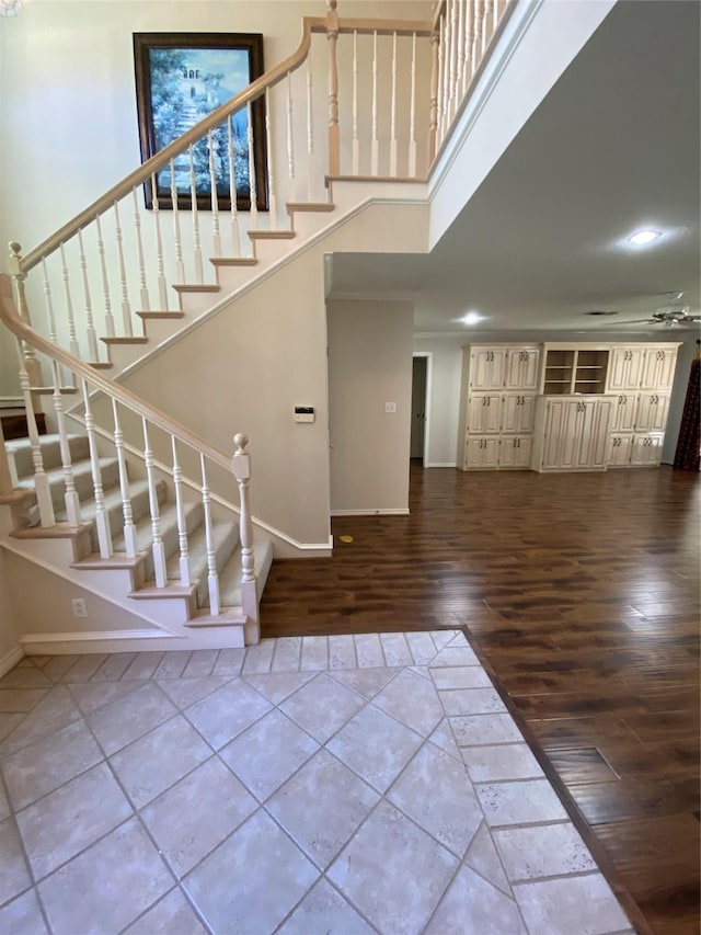 entryway featuring a towering ceiling, baseboards, stairs, and wood finished floors