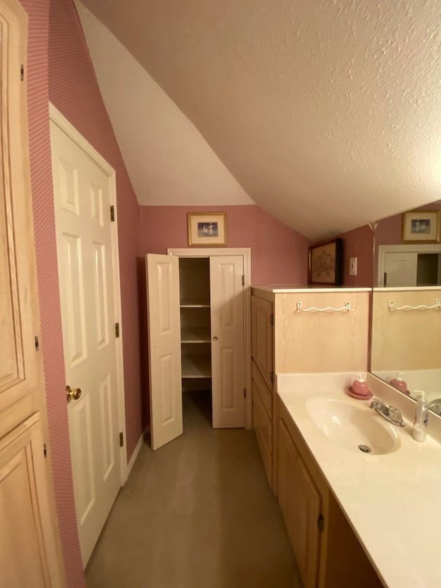 bathroom featuring lofted ceiling, vanity, and a textured ceiling