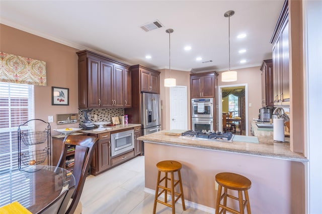 kitchen featuring appliances with stainless steel finishes, ornamental molding, decorative backsplash, decorative light fixtures, and kitchen peninsula