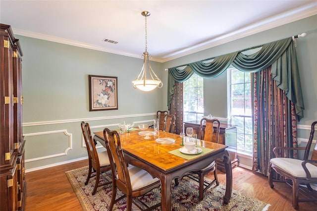 dining space featuring dark hardwood / wood-style flooring, ornamental molding, and a healthy amount of sunlight