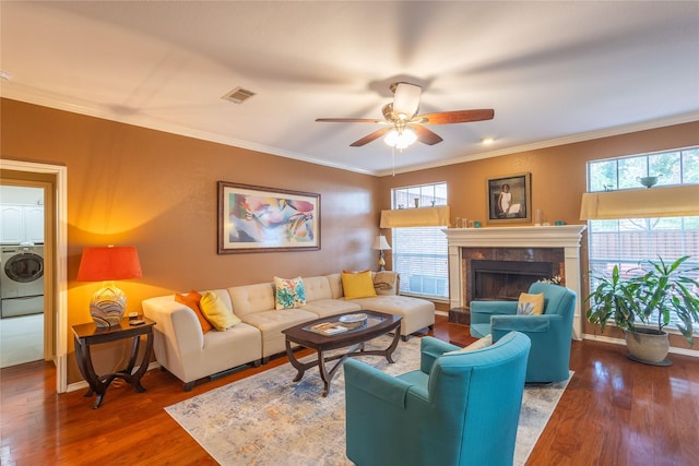 living room with ornamental molding, stacked washing maching and dryer, dark wood-type flooring, and ceiling fan