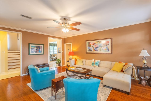 living room with crown molding, wood-type flooring, and ceiling fan