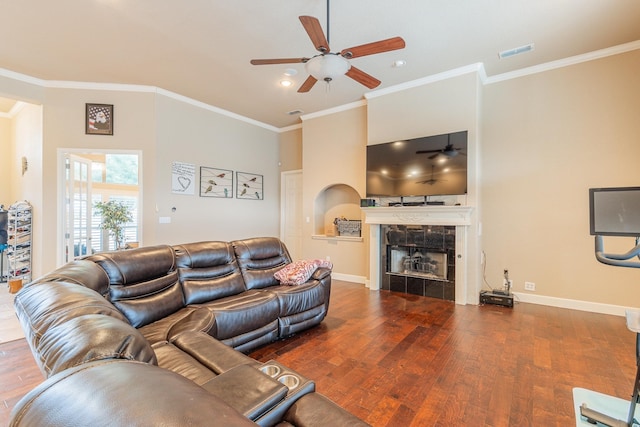 living room with a tile fireplace, ceiling fan, crown molding, and hardwood / wood-style flooring