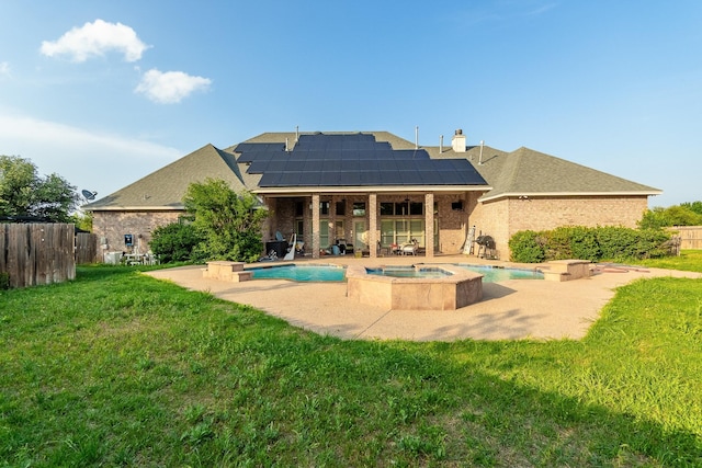 rear view of house featuring solar panels, a yard, and a pool with hot tub