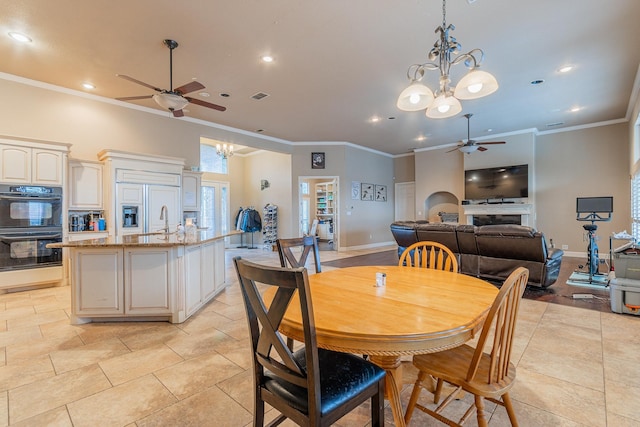 tiled dining area with sink, ceiling fan with notable chandelier, and ornamental molding