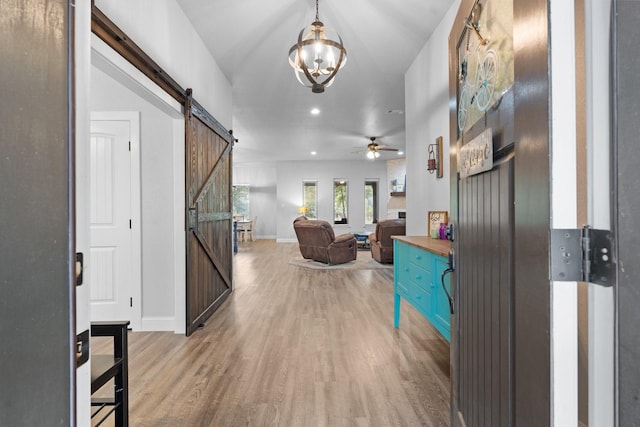 hall with a barn door, a chandelier, and light hardwood / wood-style floors