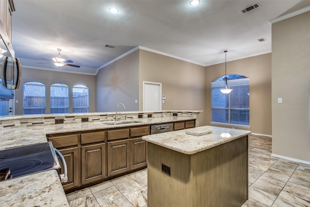 kitchen featuring light stone counters, sink, appliances with stainless steel finishes, and a kitchen island