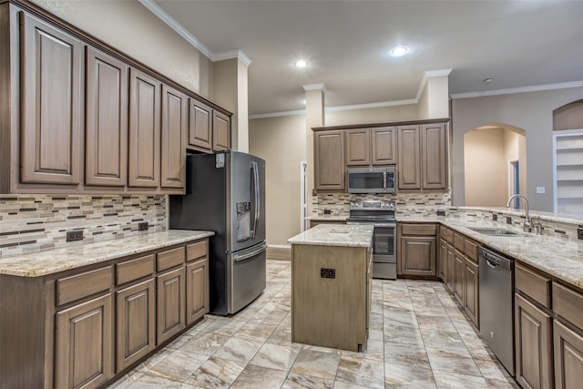 kitchen with tasteful backsplash, sink, a center island, stainless steel appliances, and light stone countertops