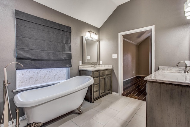 bathroom with a washtub, vanity, and lofted ceiling