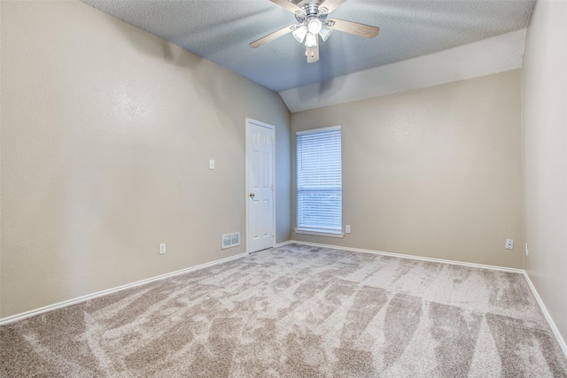 carpeted spare room featuring vaulted ceiling, a textured ceiling, and ceiling fan