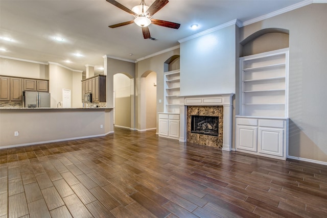 unfurnished living room featuring dark wood-type flooring, ceiling fan, ornamental molding, and a premium fireplace