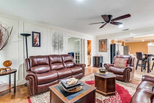 living room with ornamental molding, light wood-type flooring, and ceiling fan