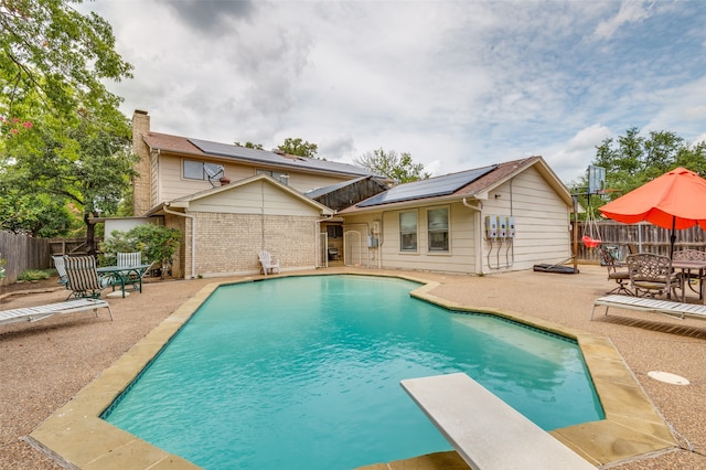 view of pool with a patio area and a diving board