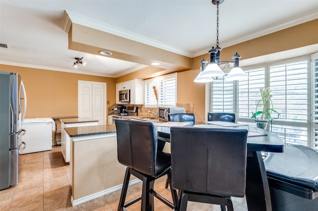 tiled dining space featuring sink and crown molding