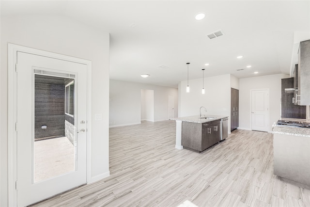 kitchen featuring sink, light stone counters, hanging light fixtures, light hardwood / wood-style flooring, and stainless steel dishwasher