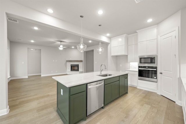 kitchen with white cabinetry, green cabinetry, an island with sink, stainless steel appliances, and sink