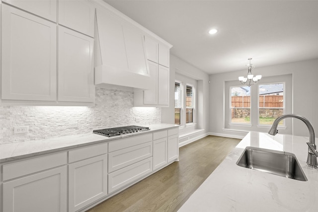 kitchen with hanging light fixtures, white cabinetry, sink, and stainless steel gas stovetop