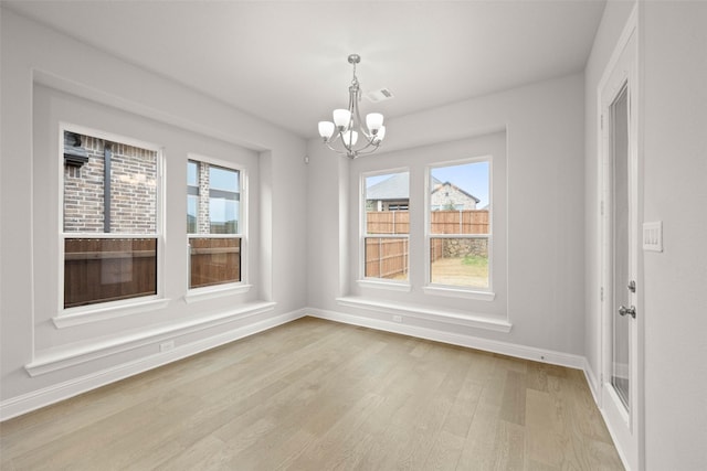 unfurnished dining area featuring light hardwood / wood-style floors, plenty of natural light, and a chandelier