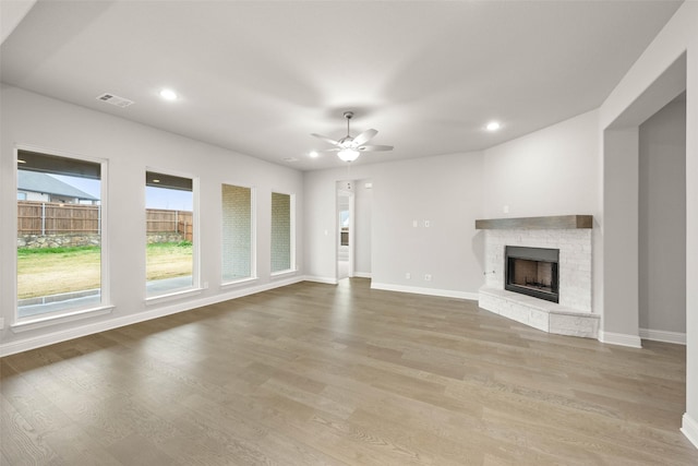 unfurnished living room with a fireplace, ceiling fan, and light wood-type flooring