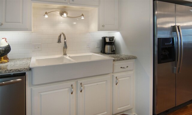 kitchen with decorative backsplash, light stone counters, stainless steel appliances, and white cabinetry