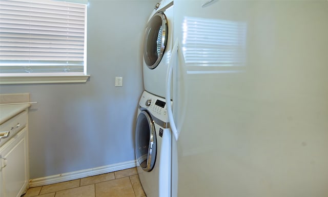 washroom with stacked washing maching and dryer, cabinets, and light tile patterned floors