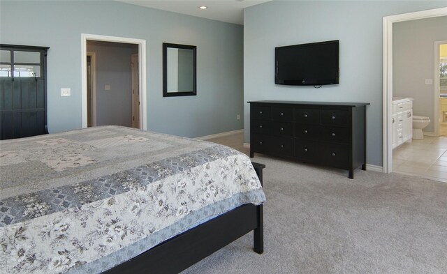 bedroom featuring ensuite bathroom, multiple windows, and light colored carpet