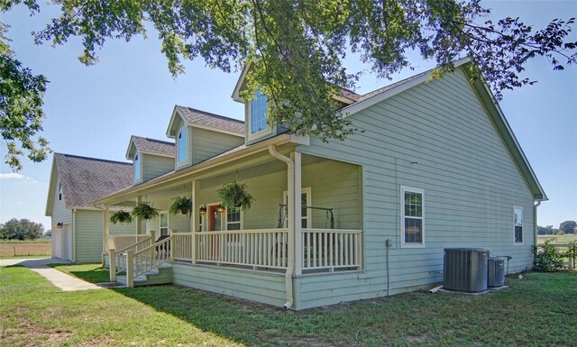 view of home's exterior featuring a garage, a porch, cooling unit, and a lawn