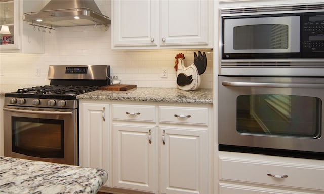 kitchen with tasteful backsplash, white cabinets, stainless steel appliances, light stone countertops, and extractor fan