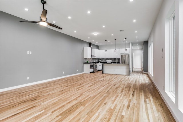 kitchen with a center island, appliances with stainless steel finishes, pendant lighting, decorative backsplash, and white cabinets