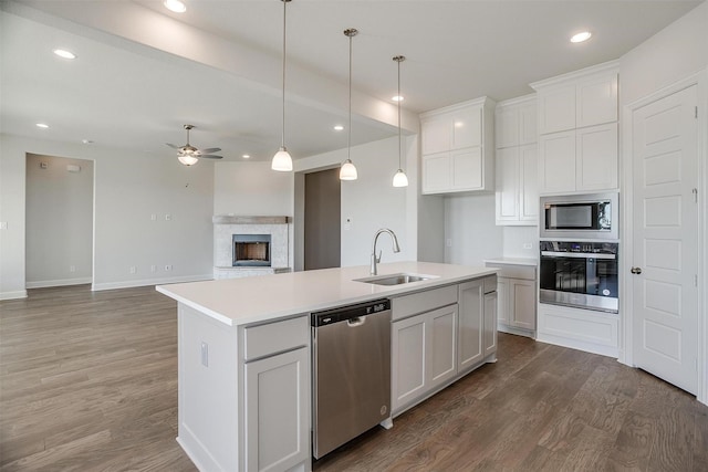 kitchen with a kitchen island with sink, sink, ceiling fan, appliances with stainless steel finishes, and white cabinetry