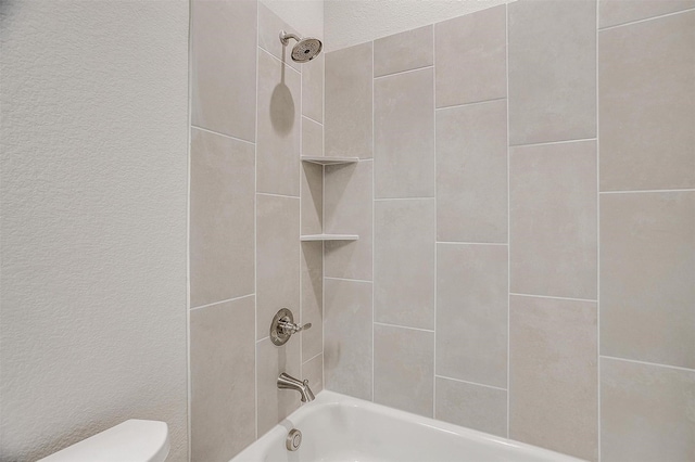 bathroom with tiled shower / bath combo and toilet