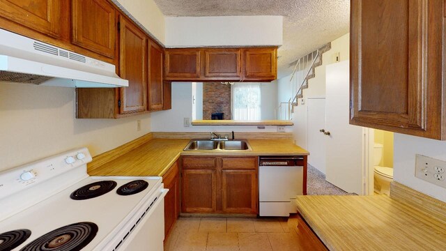 kitchen featuring stove, sink, light tile patterned floors, a textured ceiling, and dishwasher