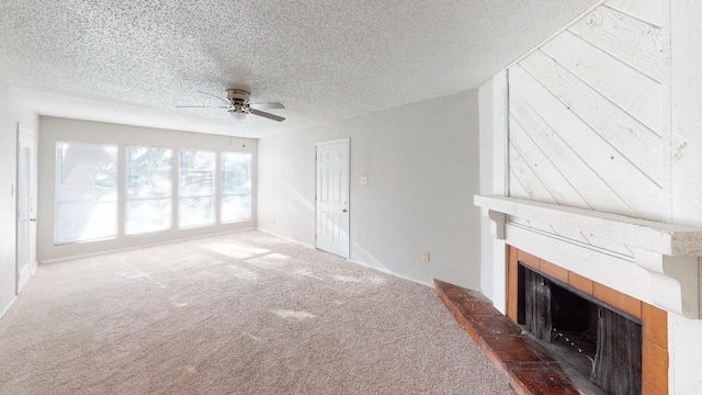 unfurnished living room featuring carpet flooring, a textured ceiling, a tiled fireplace, and ceiling fan