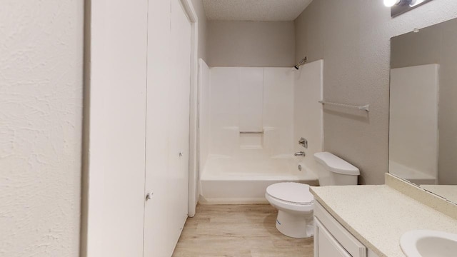 full bathroom featuring vanity, shower / bathing tub combination, wood-type flooring, a textured ceiling, and toilet