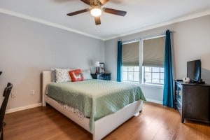 bedroom with ornamental molding, wood-type flooring, and ceiling fan