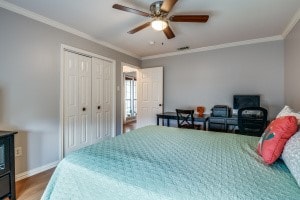 bedroom with ceiling fan, hardwood / wood-style flooring, ornamental molding, and a closet