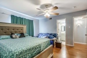 bedroom with ensuite bath, light wood-type flooring, and ceiling fan