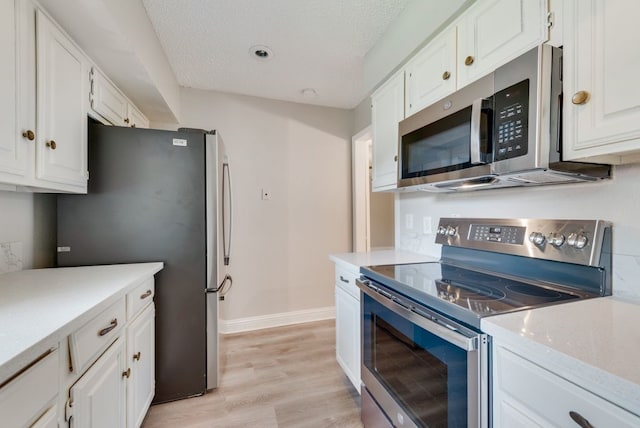 kitchen with appliances with stainless steel finishes, light wood-type flooring, a textured ceiling, and white cabinets