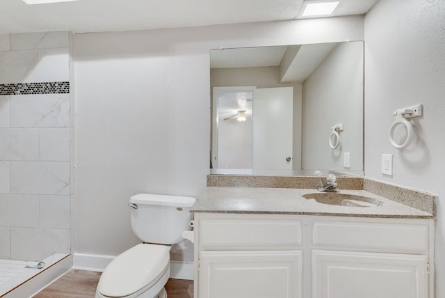 bathroom featuring hardwood / wood-style floors, vanity, a tile shower, and toilet