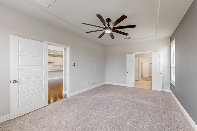 unfurnished bedroom with light carpet, sink, and ceiling fan