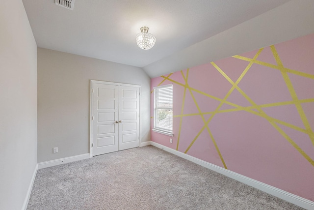 unfurnished bedroom featuring lofted ceiling, carpet floors, and a closet