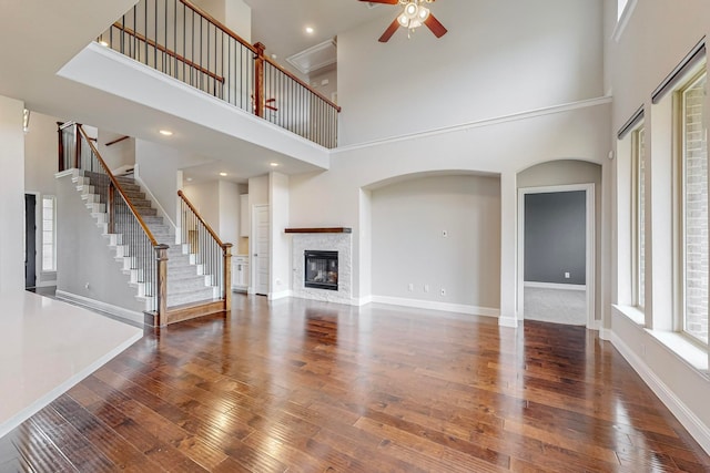 unfurnished living room featuring wood-type flooring, ceiling fan, and a towering ceiling