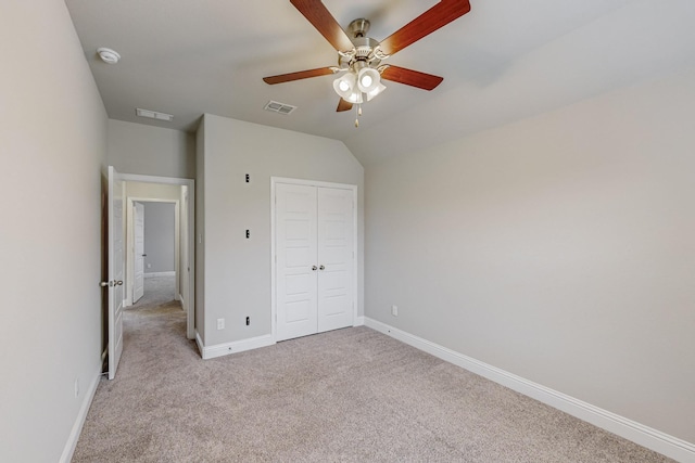 unfurnished bedroom with vaulted ceiling, light colored carpet, ceiling fan, and a closet