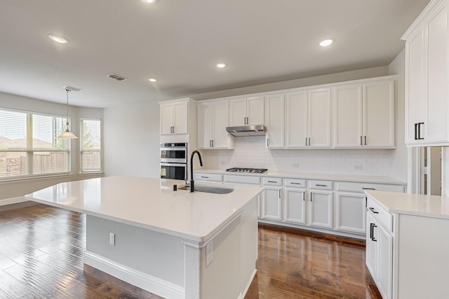 kitchen featuring white cabinetry and an island with sink