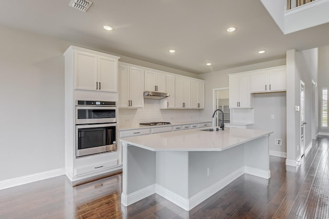 kitchen featuring appliances with stainless steel finishes, white cabinetry, sink, a kitchen island with sink, and dark wood-type flooring