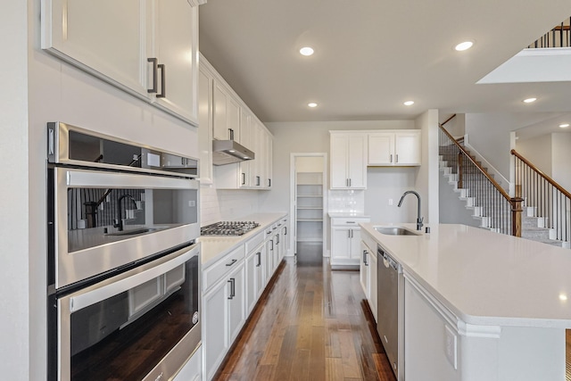 kitchen featuring white cabinetry, appliances with stainless steel finishes, a kitchen island with sink, and sink