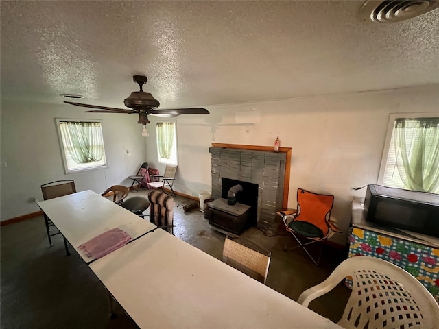 living room with a fireplace, a textured ceiling, and ceiling fan